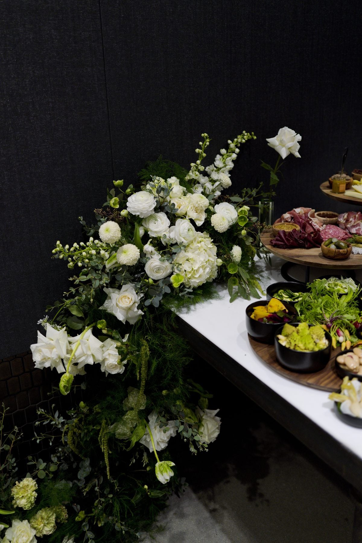 White and green corporate event floral installation beside a grazing table, by Adore Flowers, Los Angeles