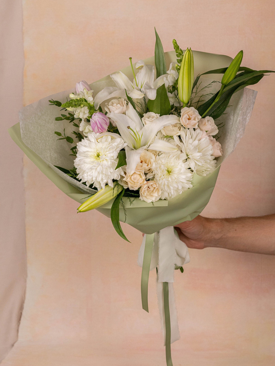 A white sympathy arrangement of lilies, mini roses, and chrysanthemums