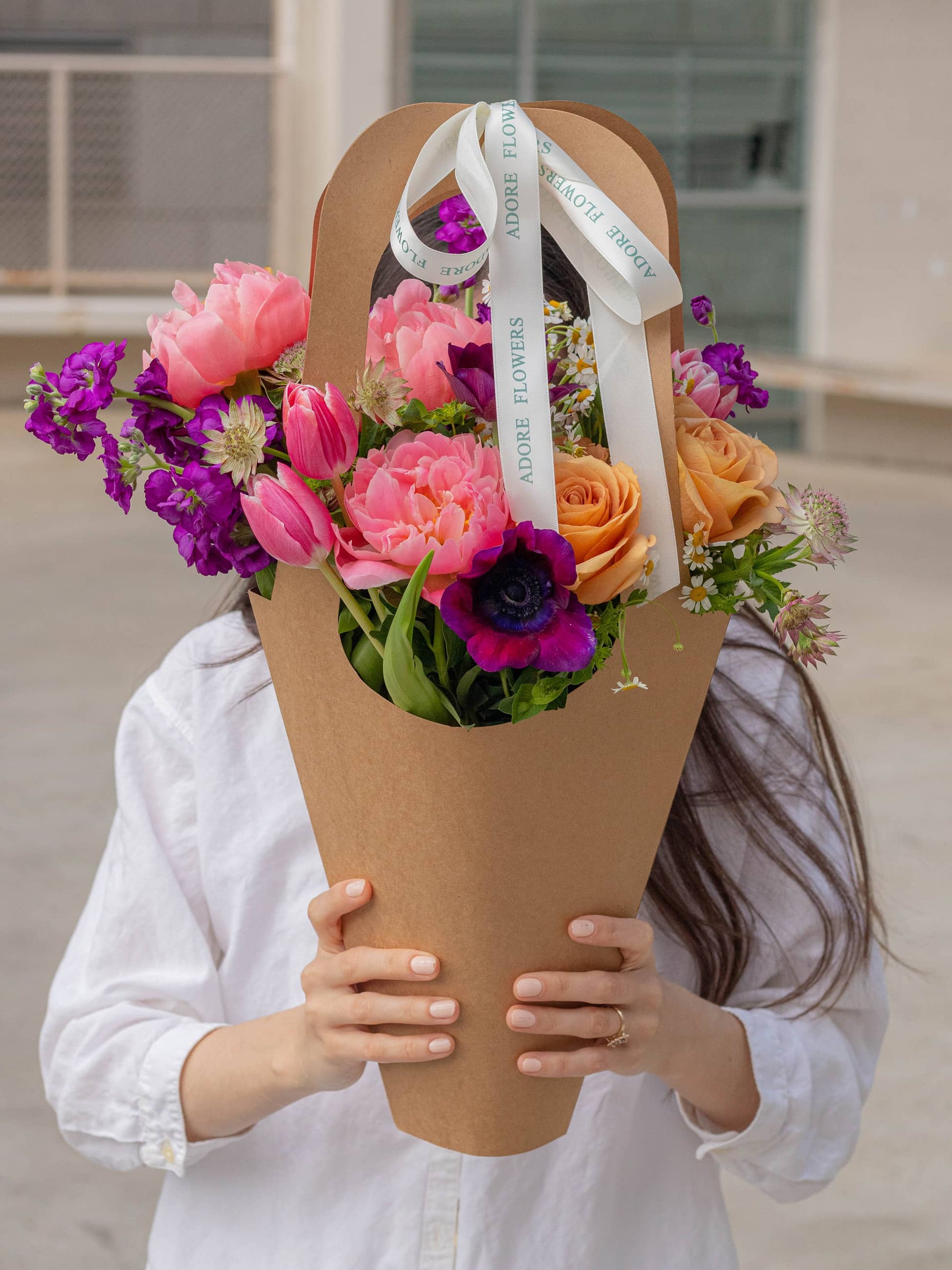 Gorgeous Blooms Flower Arrangement in a Paper Bag held for size showcase - Stunning Pink and Purple Flowers for Special Occasions