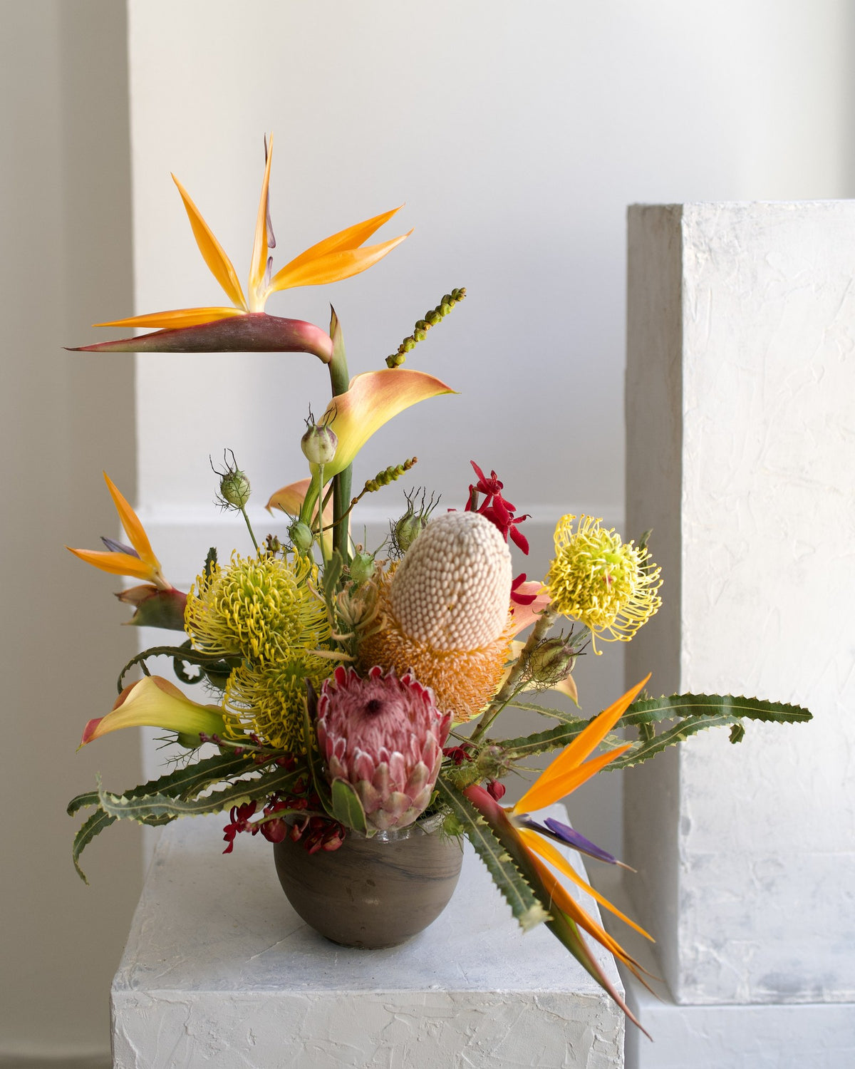 Custom designer arrangement, florist's choice with bird of paradise, pink protea, yellow pincushion protea and banksia in a stoneware vase, Adore Flowers Los Angeles