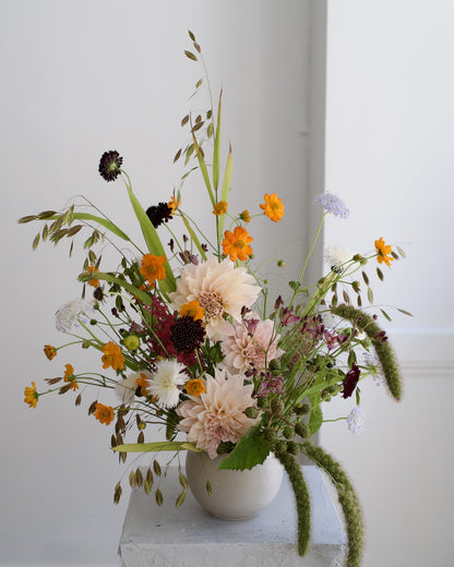Wildflower vase arrangement variation with cafe au lait dahlias, orange cosmos, burgundy scabiosa and wild grasses in a cream ceramic vase, The Wild Bunch by Adore Flowers Los Angeles